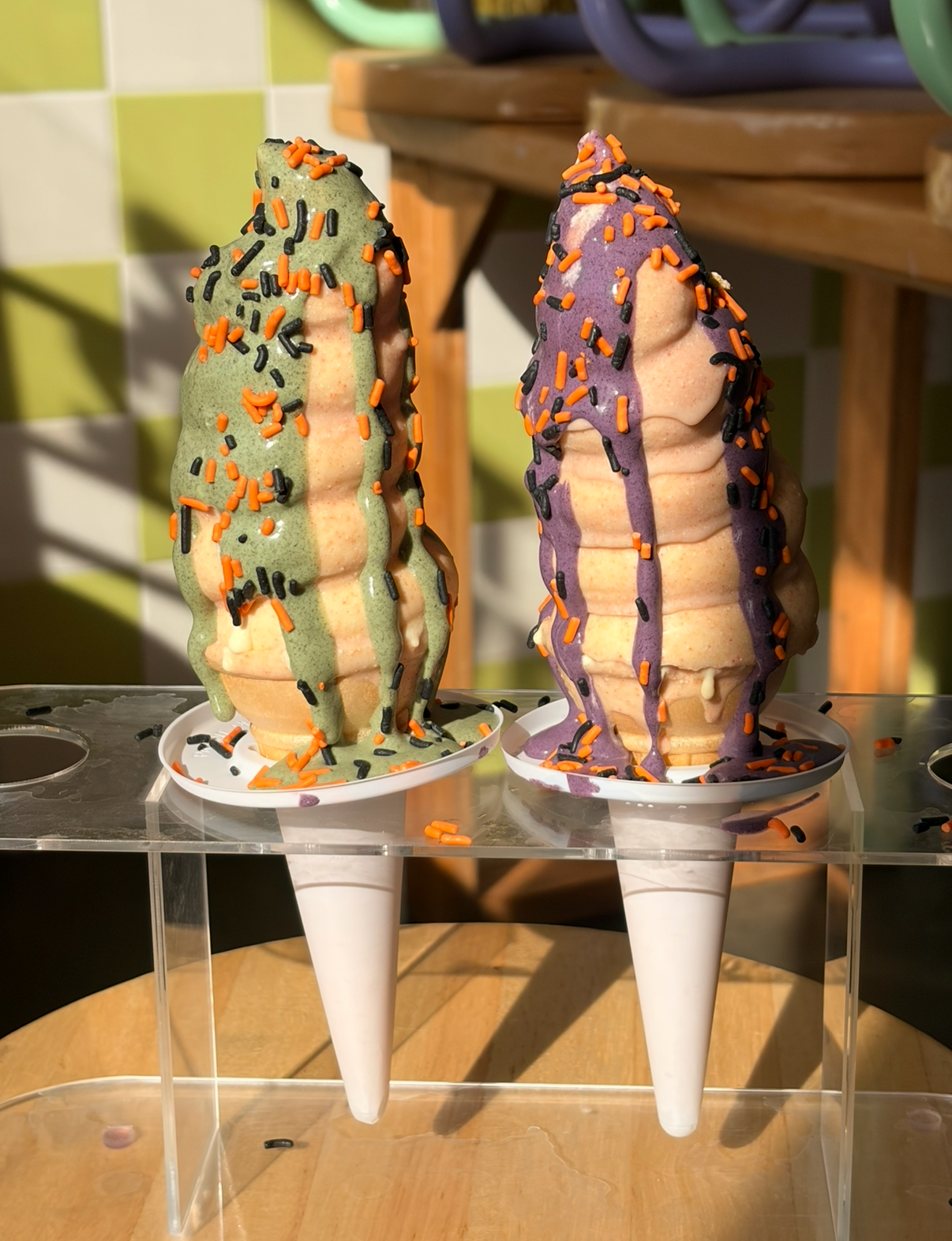 Two Thai tea dipped cones with green and purple sauce and Halloween sprinkles